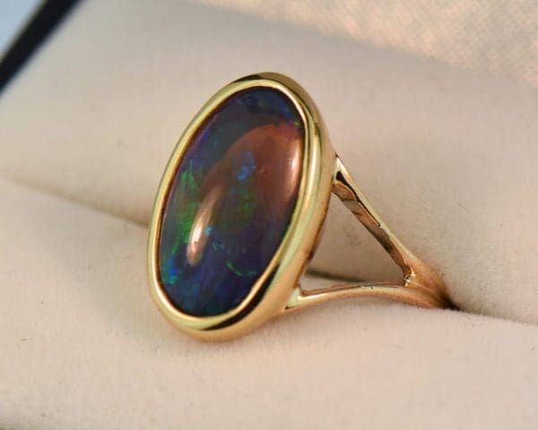 oval black crystal opal solitaire ring in yellow gold bezel with split shank 2