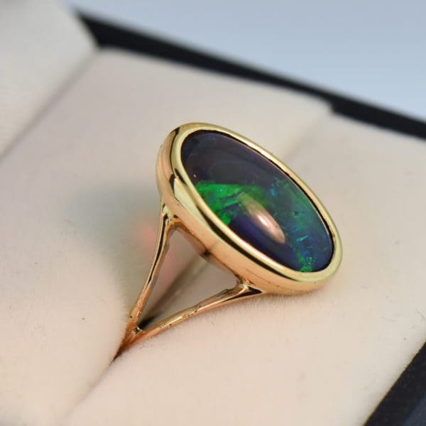 oval black crystal opal solitaire ring in yellow gold bezel with split shank 3