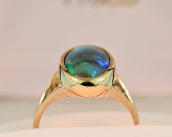 oval black crystal opal solitaire ring in yellow gold bezel with split shank 4