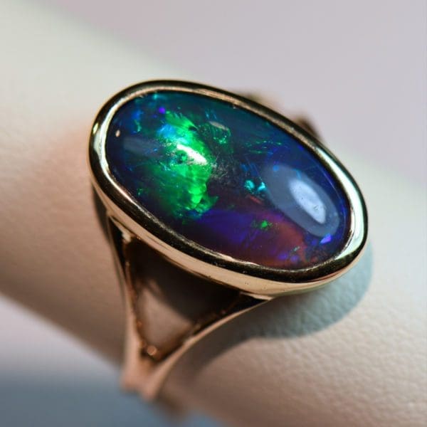 oval black crystal opal solitaire ring in yellow gold bezel with split shank 6