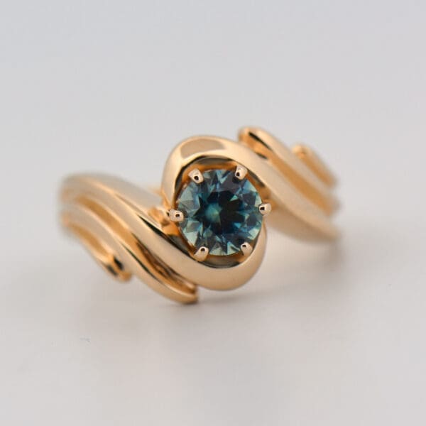 custom yellow gold swirl ring with teal montana sapphire