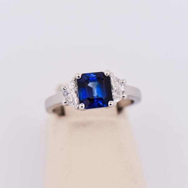 asscher cut blue sapphire and half moon diamond three stone ring