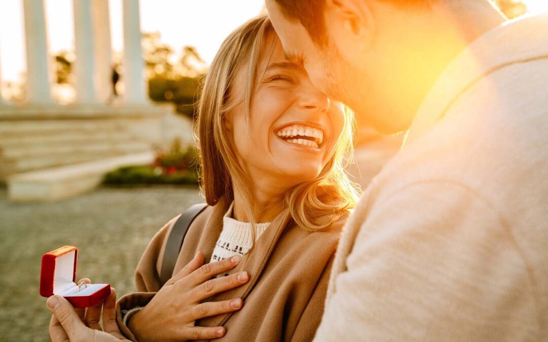 White man smiling and proposing to his girlfriend in park